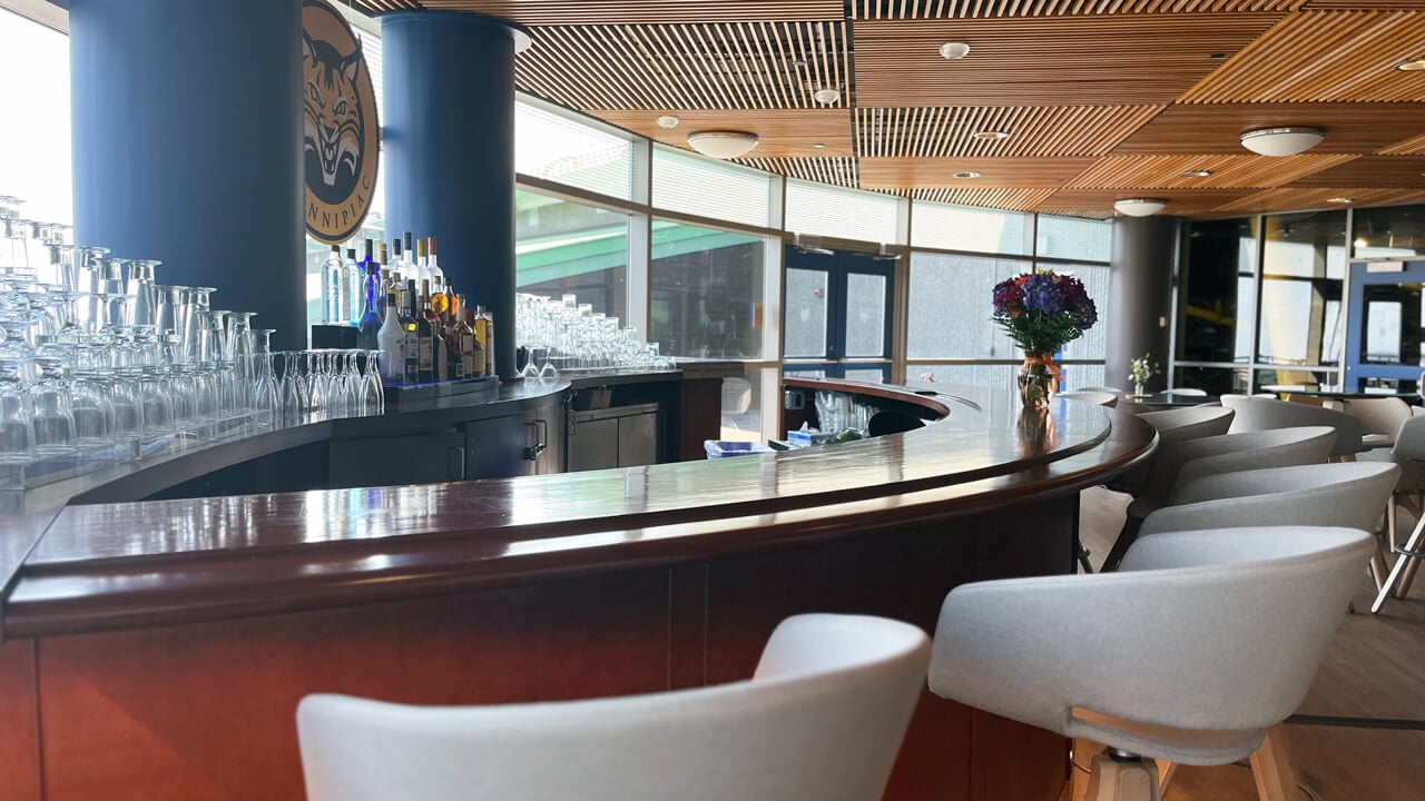 A fully stocked, crescent-shaped bar with upholstered chairs around it