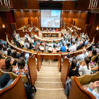 The ceremonial courtroom full of participants and a large projector screen at the front