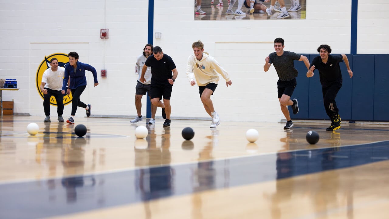 Half a dozen people run in a game of dodgeball in the recreation center